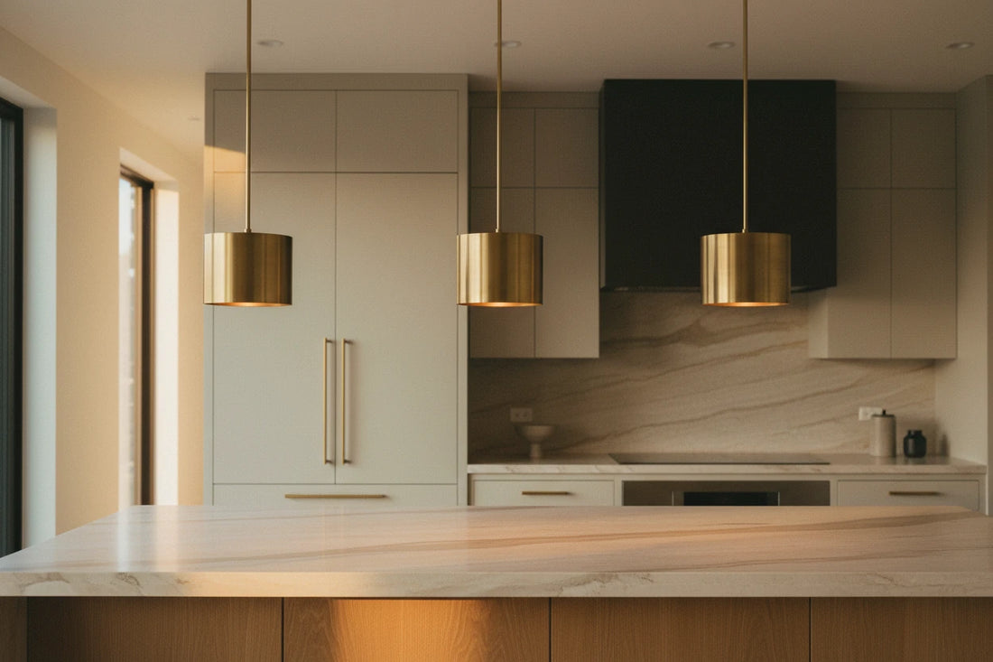 Three brass pendants evenly spaced over a warm kitchen island at golden hour