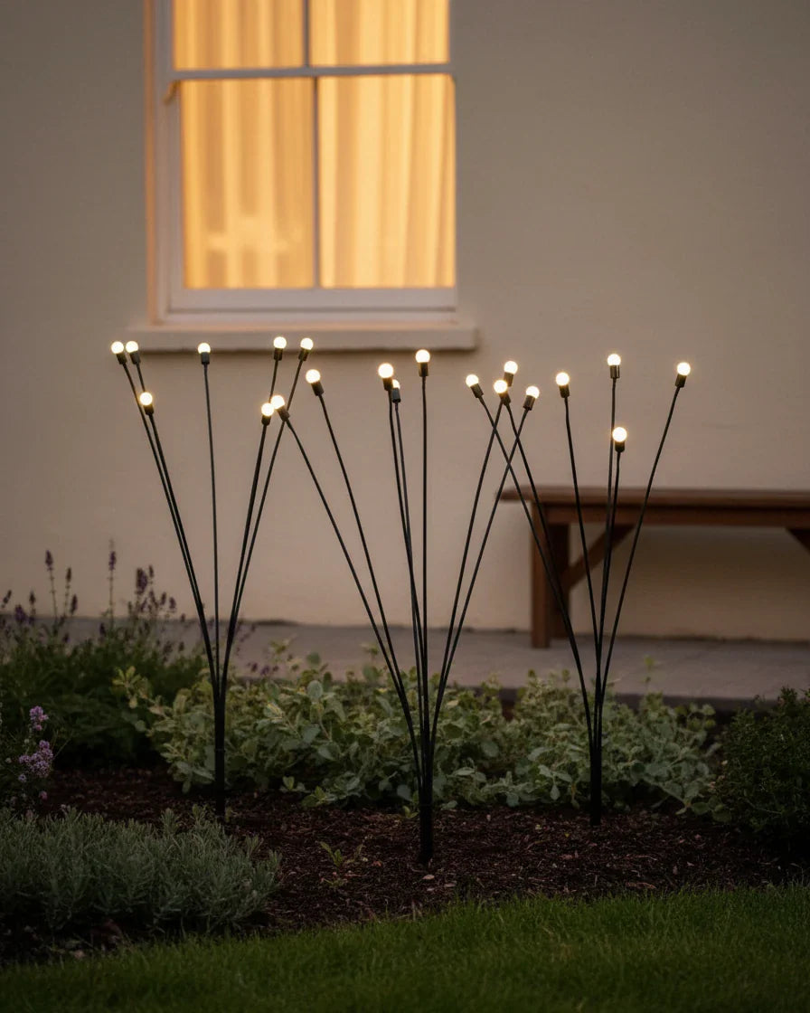 Aureline solar firefly lights glowing warm white in an outdoor garden at dusk