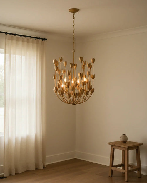 Aureline tiered bloom chandelier in burnished gold, lit in a living room setting