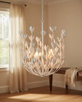 Aureline tiered flower chandelier in burnished gold, lit, hanging in a living room - Plaster White