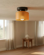 Aurelis round glass plafond in warm orange, flush mounted on a white ceiling, softly lit
