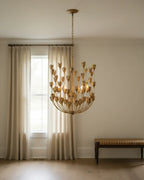 Aurelis tiered petal chandelier in burnished gold, lit, hanging in a living room