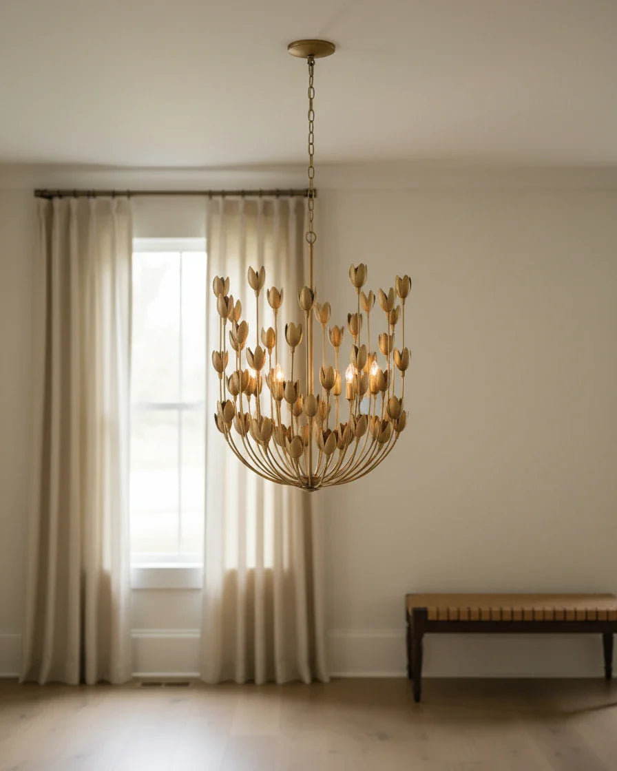 Aurelis tiered petal chandelier in burnished gold, lit, hanging in a living room
