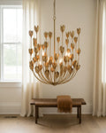 Aurelis tiered petal chandelier in burnished gold, lit, hanging in a living room