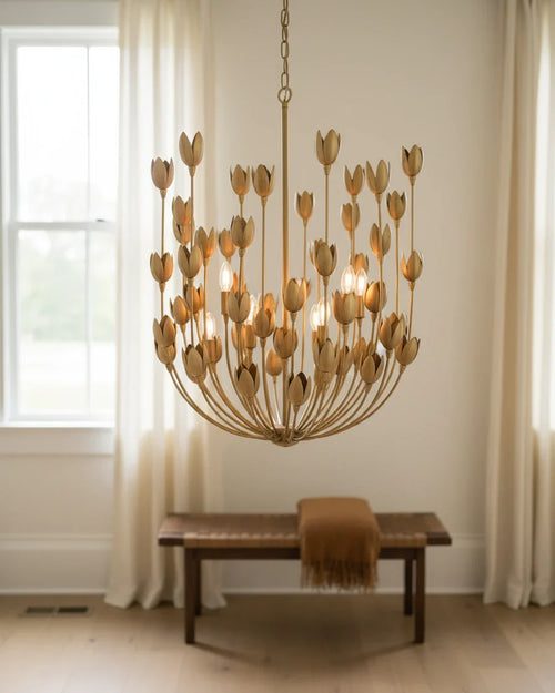 Aurelis tiered petal chandelier in burnished gold, lit, hanging in a living room