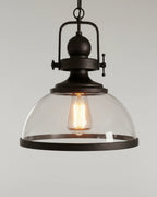 Industrial-style pendant light with a matte black iron frame and clear glass bowl shade lit over a marble kitchen island - detail 4