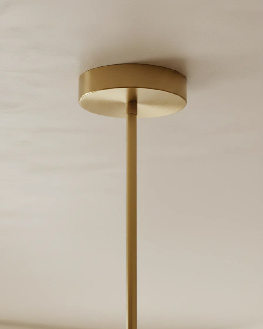 Modern linear island pendant with cylindrical gold and black shades on a horizontal bar, lit over a marble counter. - detail 1