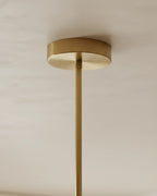 Modern linear island pendant with cylindrical gold and black shades on a horizontal bar, lit over a marble counter. - detail 1