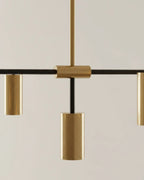 Modern linear island pendant with cylindrical gold and black shades on a horizontal bar, lit over a marble counter. - detail 3