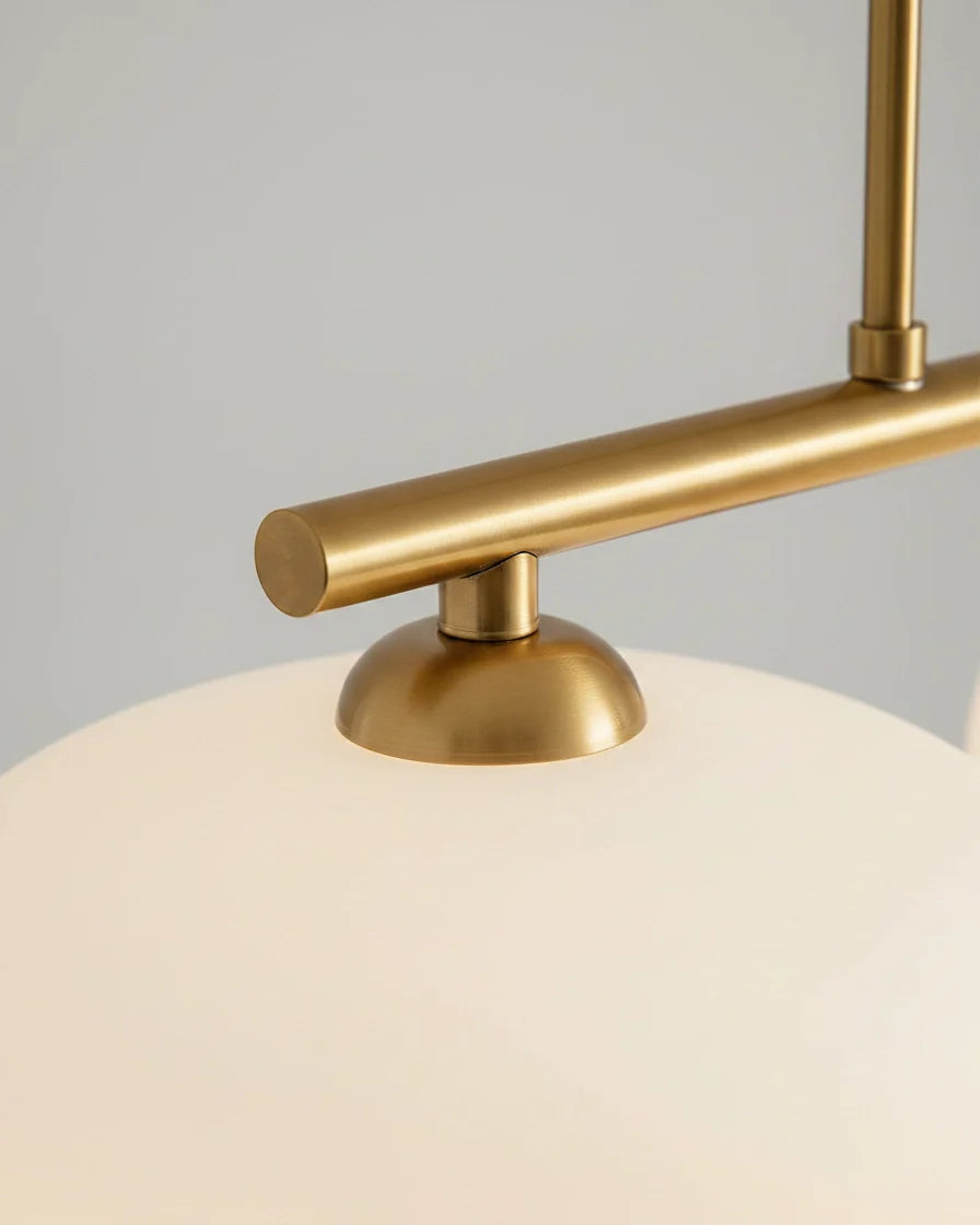 Linear 3-light pendant with gold finish and three spherical white glass shades, lit, in a kitchen setting - detail 3